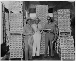 Photograph of the Memphis Belle crewmen standing in front of stacks of magnesium ingots