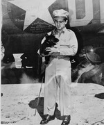 Photograph of a Memphis Belle crewman holding a dog in front of the Memphis Belle