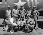 Photograph of a Memphis Belle crewmen and F.O. Case holding a sign in front of the Memphis Belle