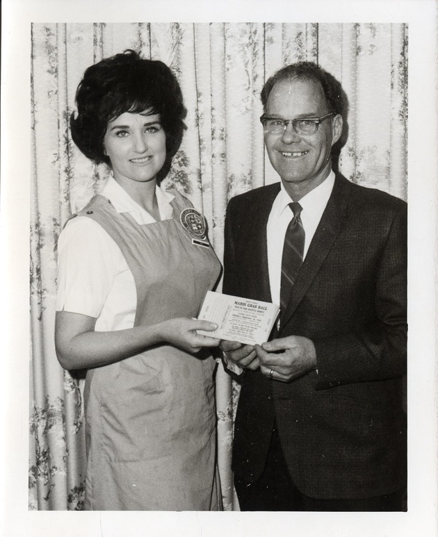 Photograph of Rose de Lima Hospital Auxiliary member and a man holding Mardi Gras Ball tickets, Henderson