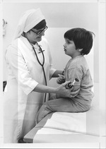 Photograph of Sister Singer examining a child at Rose de Lima Hospital, Henderson