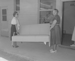 Photograph of women moving a sofa, Henderson, October 7, 1955