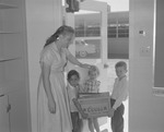 Photograph of children carrying a box into a classroom at Park Village Elementary School, Henderson, October 7, 1955