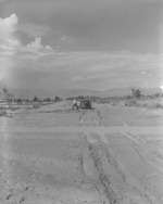 Photograph of a man shoveling his car out of the mud, Henderson, July 24, 1955