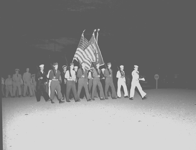 Photograph of men marching and holding flags in the Veteran's Day celebration, Henderson, November 11, 1946